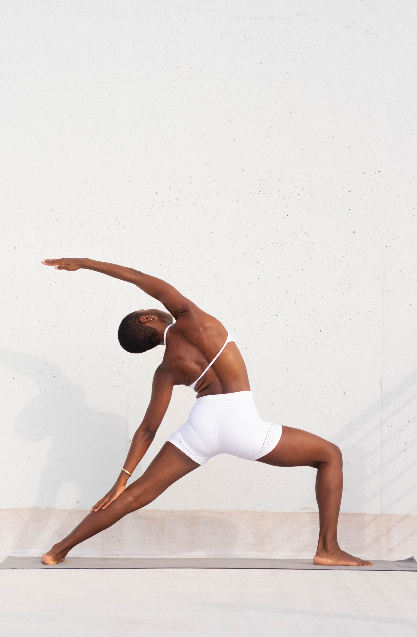 Athletic movement portrait in white against a sunlit wall