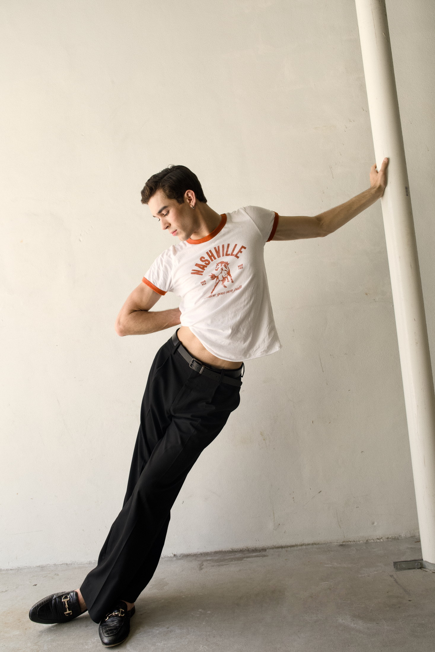 Editorial menswear movement portrait leaning against a minimal wall