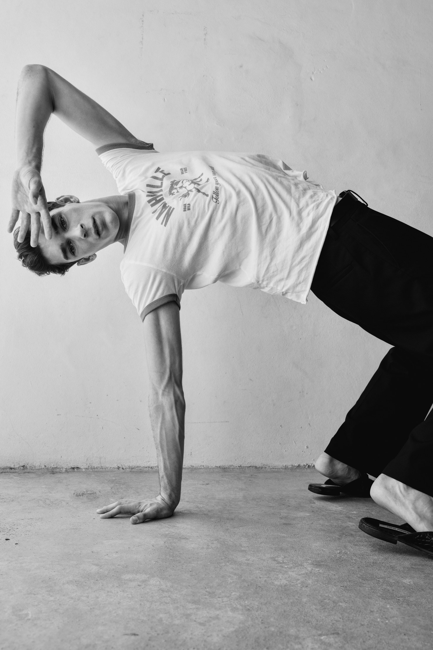 Black-and-white movement portrait against a minimal wall