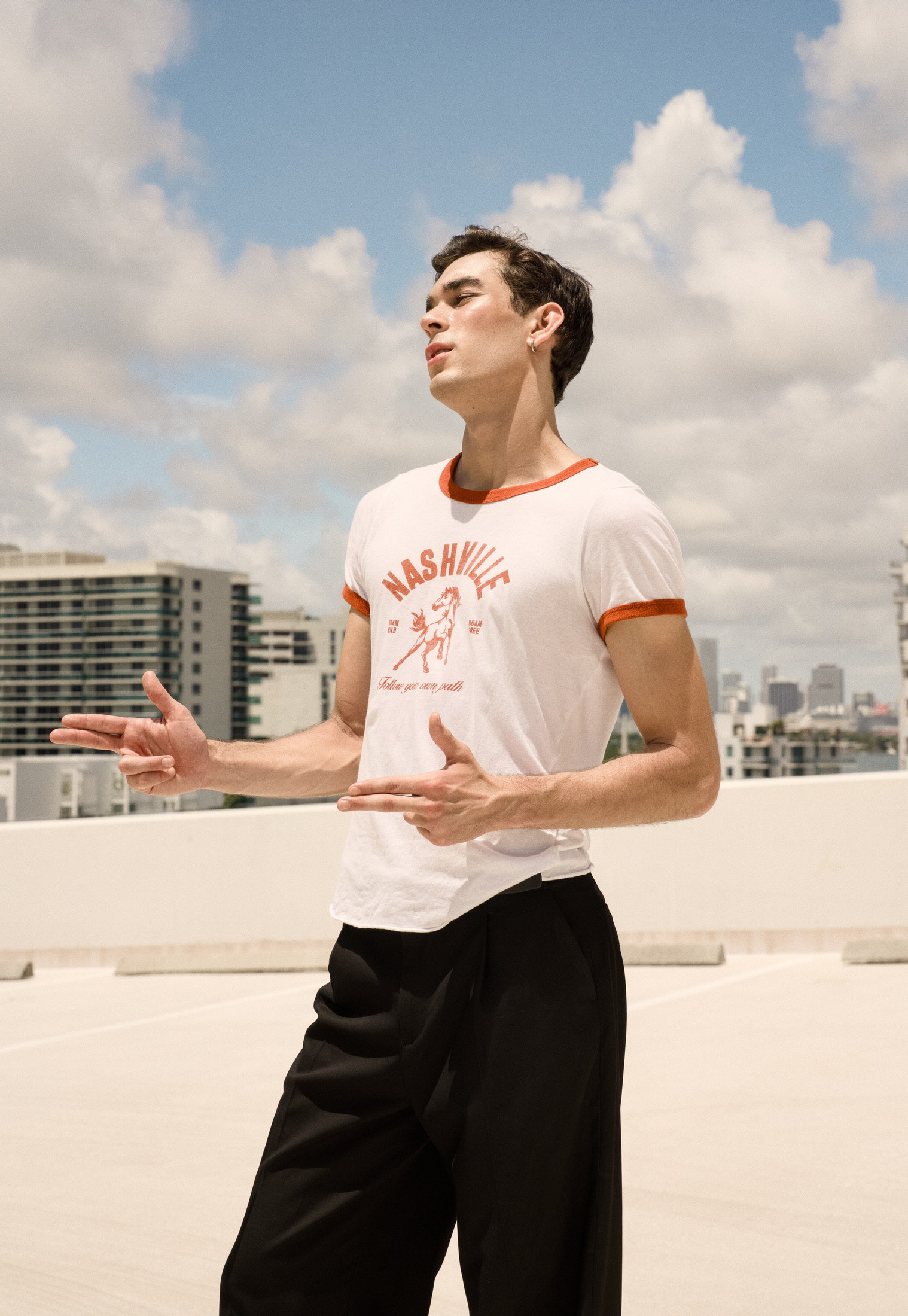 Rooftop menswear portrait beneath bright summer clouds