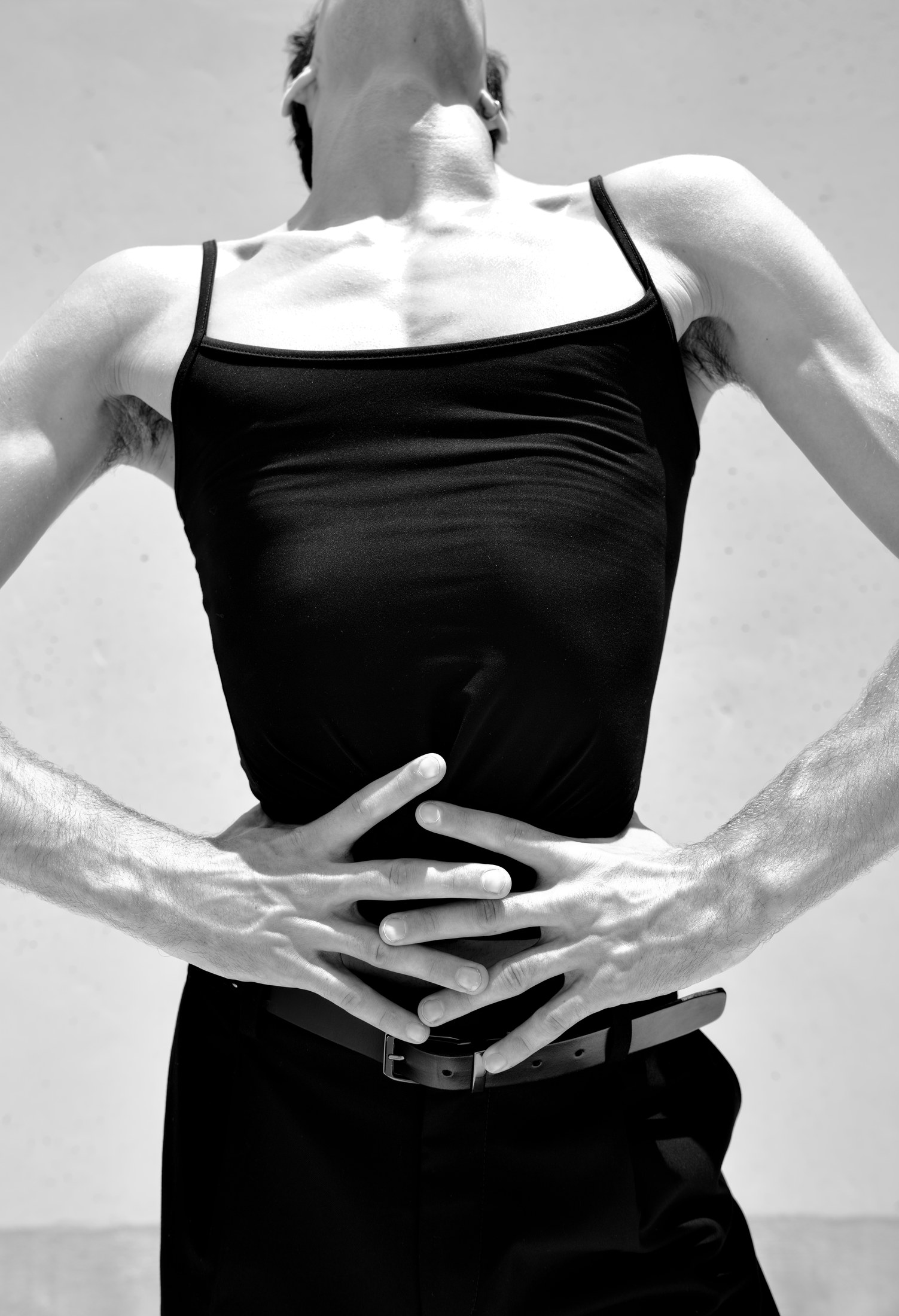 Black-and-white sculptural portrait of torso and interlocked hands