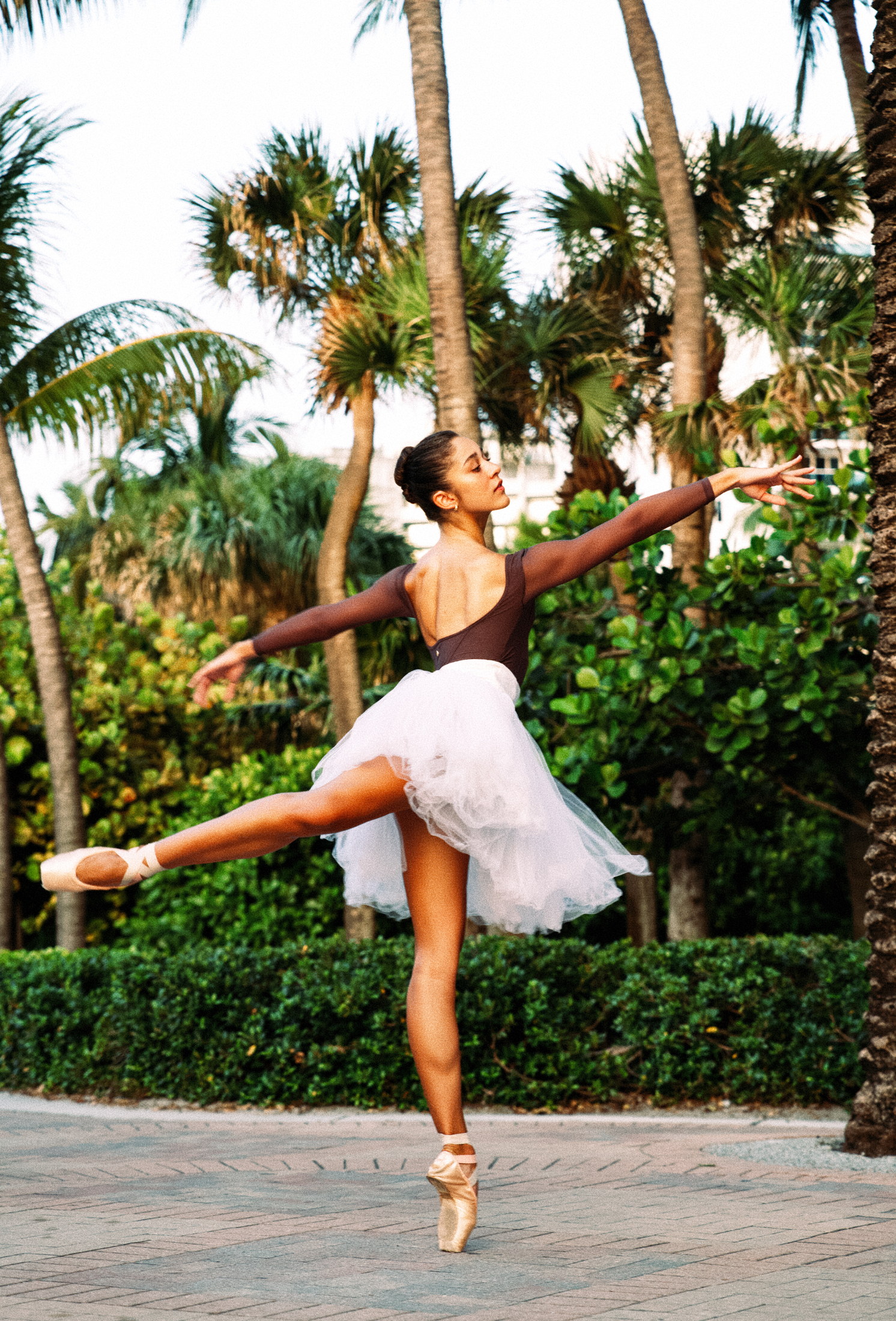 Ballet portrait in a white tutu against saturated tropical green