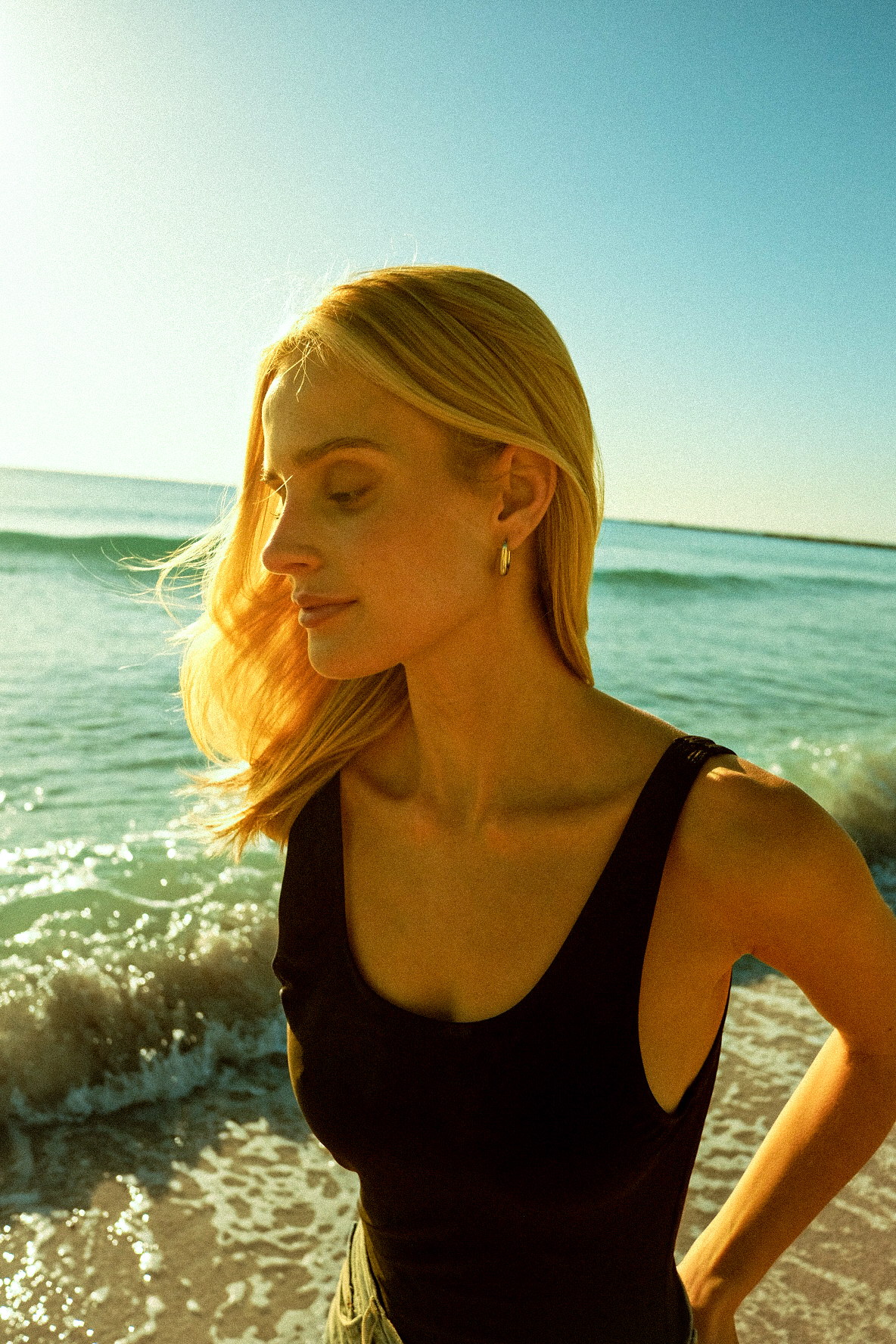 Golden-hour fashion portrait standing by the ocean