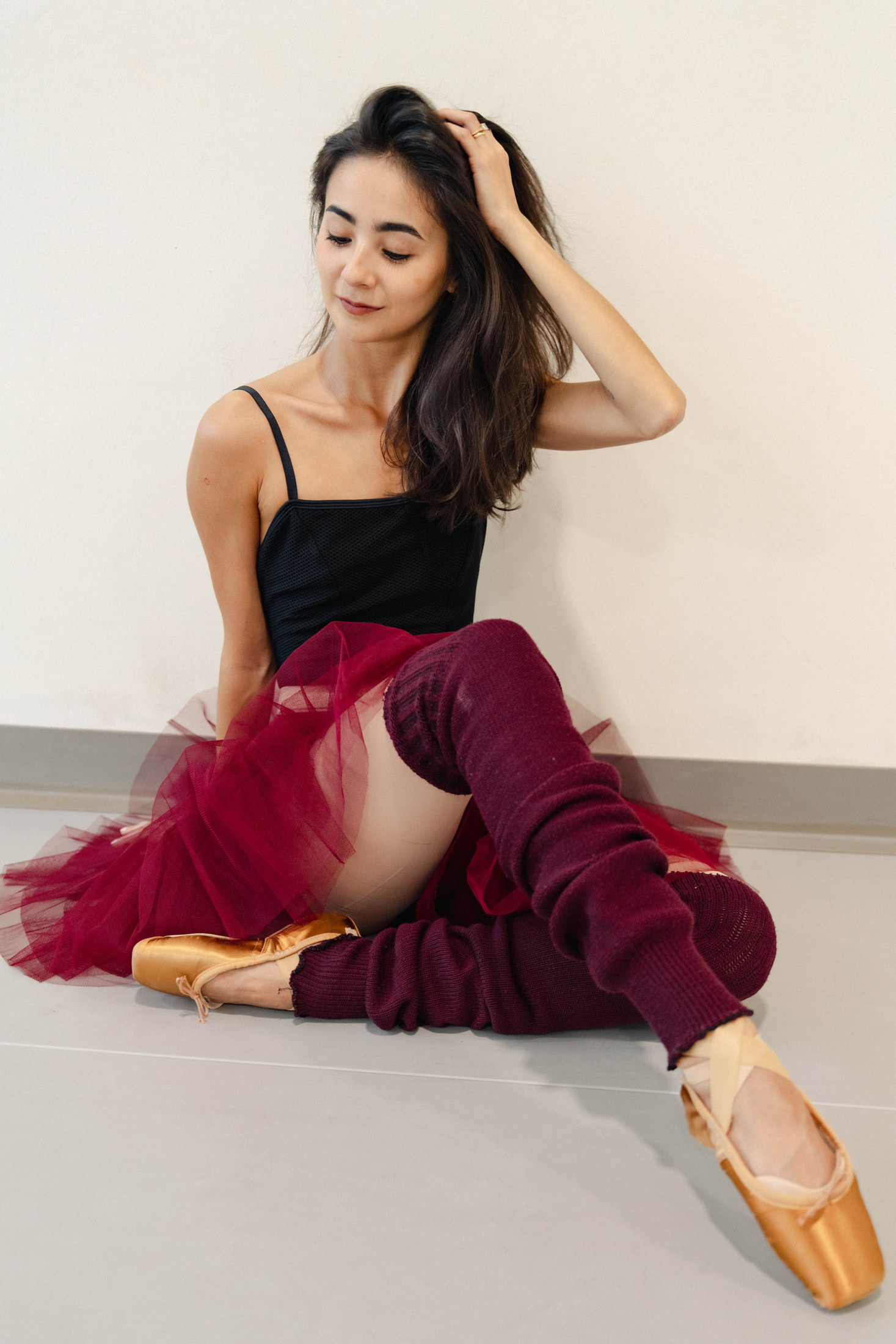 Seated ballet portrait in black, red tulle, and red leg warmers